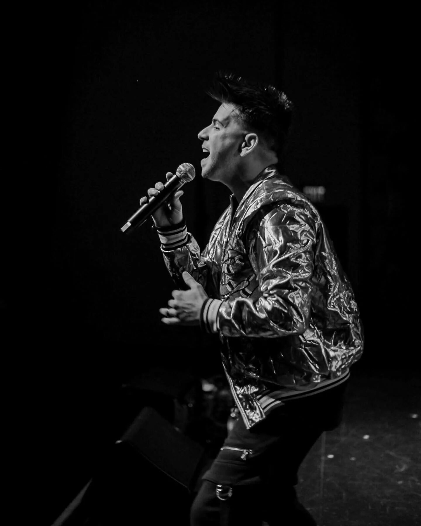Edgar René de perfil cantando al micrófono en el escenario, fotografía en blanco y negro