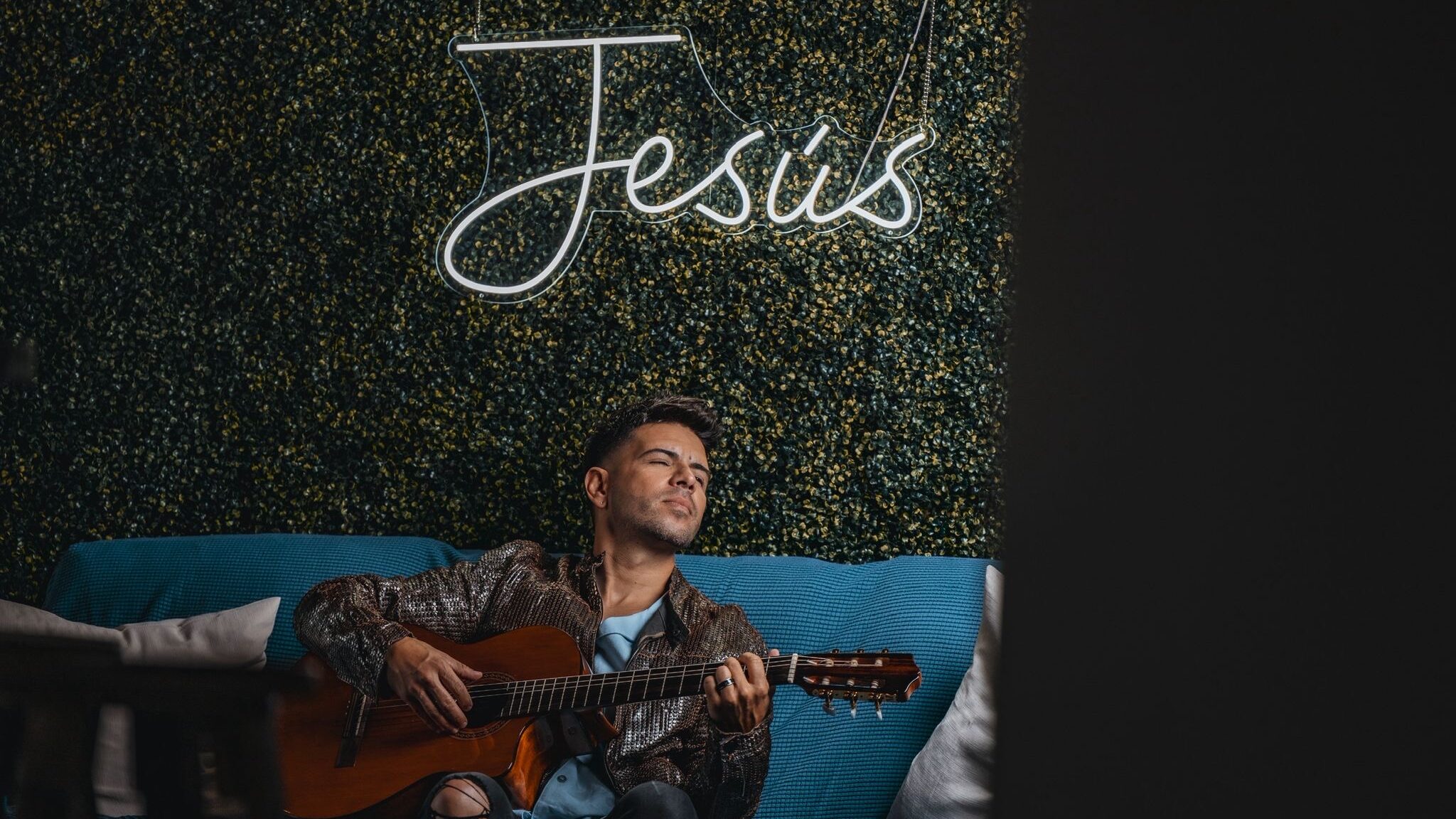 Edgar René tocando la guitarra sentado en un sofá